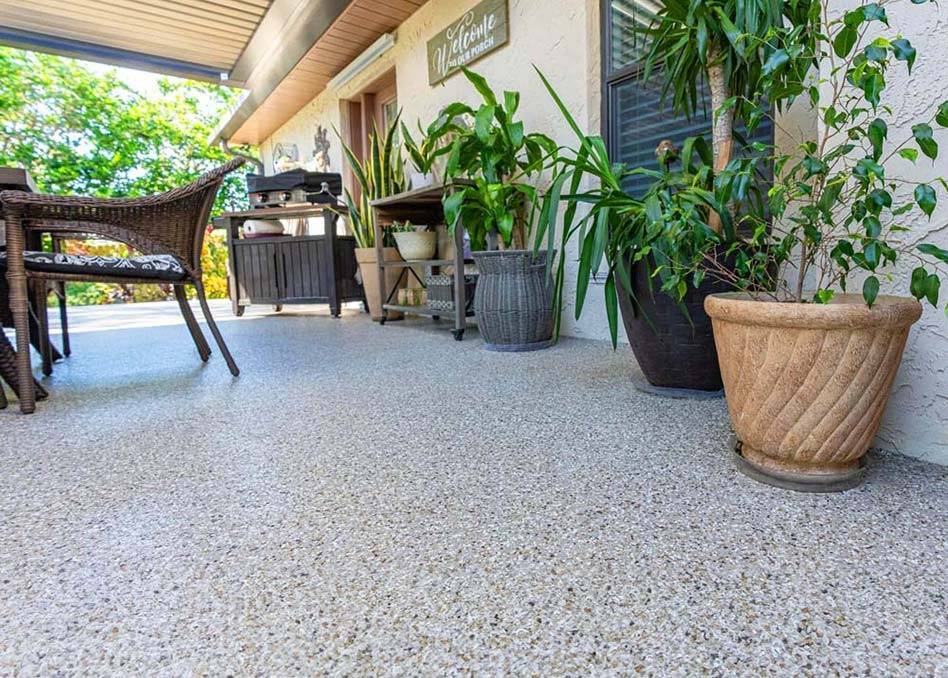 a patio with a chair and potted plants on concrete coated floor